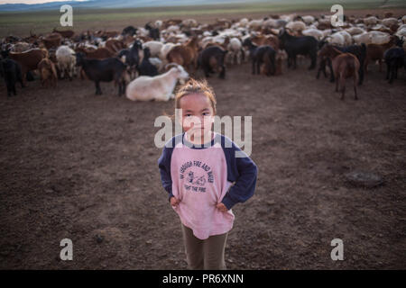 Una bambina guardando la fotocamera anteriore del bestiame qualche chilometro di distanza dal piccolo villaggio di Lün in provincia Töv, Mongolia. Foto Stock