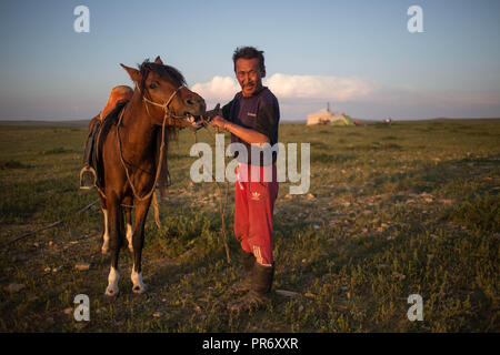 Un uomo locale visto prendersi cura del suo cavallo accanto alla piccola città di Adaatsag nella provincia Dundgovi in Mongolia centrale. Foto Stock