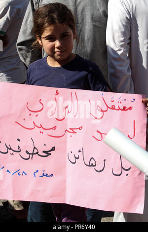 Un bambino visto tenendo un poster durante una manifestazione di protesta nella città di Eriha in Idlib per chiedere la liberazione di sei persone detenute dal regime siriano. Foto Stock