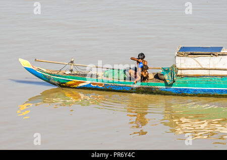 Phnom Penh Cambogia - Aprile 9, 2018: tipica coda lunga Mekong cambogiano barca con una tettoia e vive una famiglia su di esso, un uomo lavando il suo bambino Foto Stock