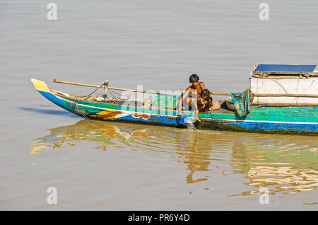 Phnom Penh Cambogia - Aprile 9, 2018: tipica coda lunga Mekong cambogiano barca con una tettoia e vive una famiglia su di esso, un uomo lavando il suo bambino Foto Stock