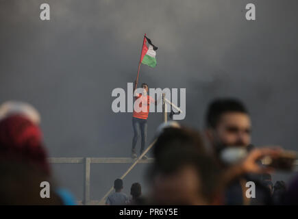 Dimostrante palestinese visto tenendo una bandiera urlando come loro stand alla frontiera Israel-Gaza recinto durante gli scontri. 7 palestinesi, compreso un 14-anno-vecchio ucciso dal fuoco israeliano durante un nuovo scontro lungo la frontiera Gaza, il ministero della sanità in controllata da Hamas striscia. Foto Stock