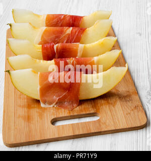 Fette di melone avvolti nel prosciutto, vista laterale. Close-up. Foto Stock