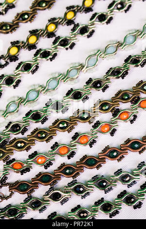 Bracciali di metallo con pietre in diversi colori su bianco tovaglia Foto Stock