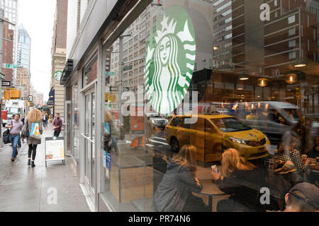 I clienti a riempire l'uno Starbucks sulla Fifth Avenue a New York City in un nuvoloso mattina di settembre. Foto Stock