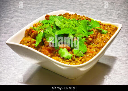 Moong Dahl, indiano vegetariano zuppa di lenticchie, in bianco ciotola. Sfondo di alluminio. Foto Stock