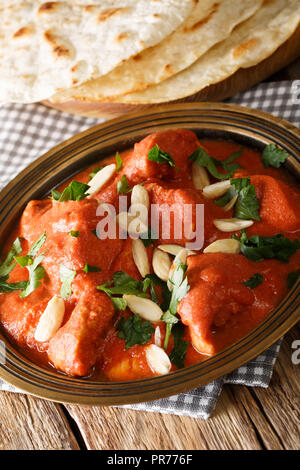 Il burro pollo Murgh Makhani cotta in un pomodoro condito con sugo di carne di close-up in una piastra con roti sul piano verticale. Foto Stock