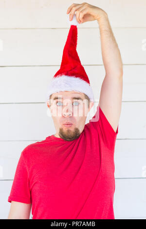 Vacanze di Natale e il concetto di abbigliamento - sorpreso funny man in costume di santa posa su sfondo bianco Foto Stock