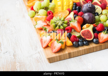 Raw sani frutti e bacche platter, Fragole Lamponi arance Prugne Mele Kiwi uve mirtilli, mango sul servizio di amministrazione, vista dall'alto, Foto Stock