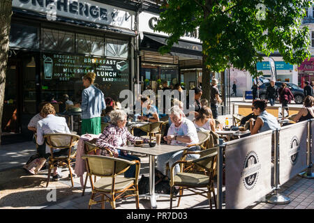 La gente seduta nella luce del sole in un cafe' sul marciapiede a Bromley Piazza del Mercato. Foto Stock