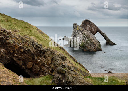 La grotta e Bow Fiddle Rock quarzite arco sul mare con spiaggia di ciottoli a Portknockie sul Mare del Nord Oceano Atlantico Scozia UK Foto Stock