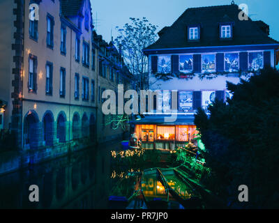 Vista da un ponte a Strasburgo, in Francia durante la notte con diverse belle luci e Windows su un fiume con barche. Il tempo di Natale Foto Stock