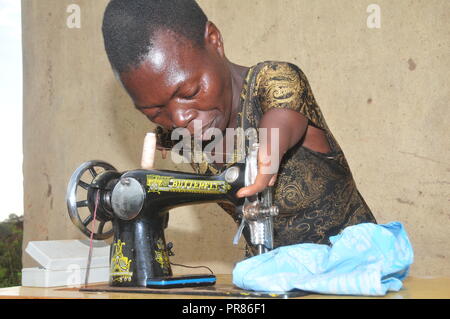 Buyende, Uganda. 29th, Settembre, 2018. Nambi Scovia da 42 anni residente del villaggio di Butaaswa nel quartiere Buyende operando una macchina da cucire. Lei fa sartoria come la sua piccola azienda. Ha dimostrato che la disabilità non è di incapacità. Questo è stato prima che le celebrazioni del suo 42o compleanno con il Ministro del Turismo di Busoga unito Hellen Namutamba (non in foto) che aveva visitato il suo. Nambi, una madre di due figli, non hanno entrambi i bracci ma dimostra al mondo che lei è in grado di lavare i suoi vestiti, fare sartoria, cucinare e occuparsi del suo giardino a procurarsi il cibo. Credito: Donald Kiirya/Alamy Live News. Foto Stock