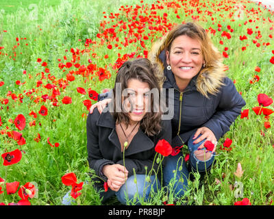 Madre spagnola e i giovani adulti figlia felice e godendo di un papavero di campo dei fiori in autunno in Spagna Foto Stock