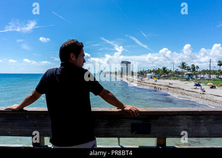 Giovane uomo guardando la vista di Dania Beach a Miami in Florida. Estate giornata soleggiata con molte persone a nuotare in acqua Foto Stock