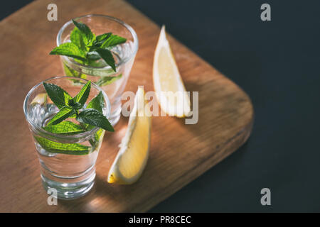 Due bicchieri di gin o vodka con menta e limone su sfondo di legno. Cocktail alcoolico. Copia dello spazio. Tonificazione. Foto Stock