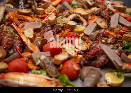 Gourmet a base di pesce paella Valencia con il polpo fresco, langoustine, vongole, cozze e calamari su gustosa riso allo zafferano con piselli e le fette di limone, close up Foto Stock