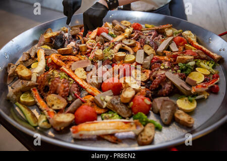 Gourmet a base di pesce paella Valencia con il polpo fresco, langoustine, vongole, cozze e calamari su gustosa riso allo zafferano con piselli e le fette di limone, close up Foto Stock