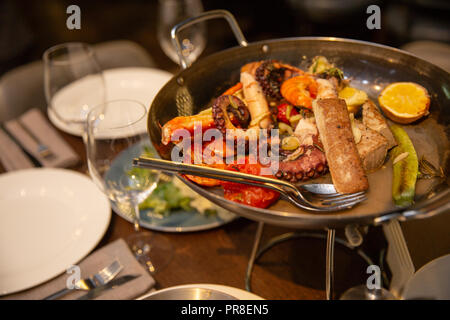 Cocktail di mare in una piastra nera. gamberi cozze, polpo, tonno, calamari e le verdure su una padella che serve frutti di mare al ristorante Foto Stock