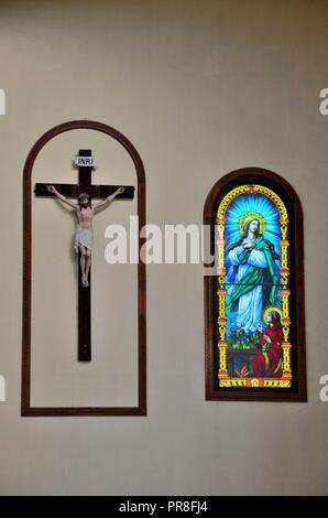 Cristo crocifisso sulla croce appesa sul muro con vetrate colorate la cattedrale di St Mary Church Jaffna nello Sri Lanka Foto Stock