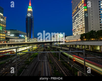 Binari del treno scorrono attraverso Shinjuku, Tokyo di notte, come visto da sud terrazza pedonale. Le striature del passaggio di treni a lungo expos Foto Stock