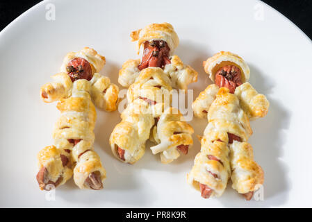 Cibo di Halloween. Salsiccia mummie in pasta cotti al forno Foto Stock