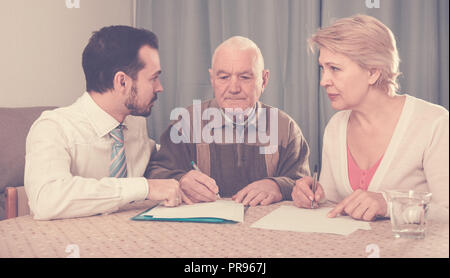 Padre e figlia matura e giovani sales manager firma contratto a casa Foto Stock