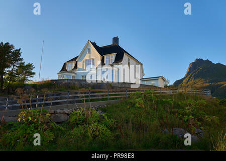 Tradizionale in legno dipinto Casa norvegese, illuminato dal sole al tramonto a Svolvaer, Isole Lofoten, Nordland County, Norvegia. Foto Stock