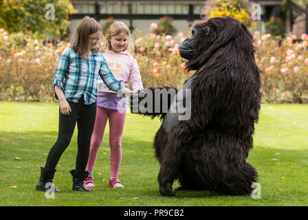 Alanna Paszkowska (sinistra) e Ella Rose interagire con un turismo Uganda life-size animatronic gorilla di montagna durante la fauna selvatica &AMP; Safari Travel Show a Harrogate Convenzione in Harrogate, Yorkshire. Foto Stock