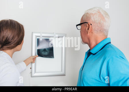 Medico la revisione delle immagini a raggi x con paziente anziano in ufficio medici Foto Stock
