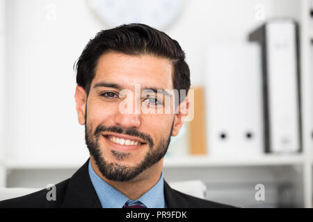 Ritratto di sorridere imprenditore che è al suo posto di lavoro in ufficio. Foto Stock