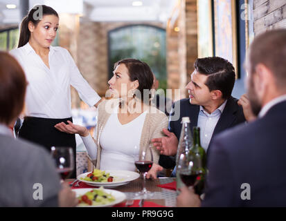 Società di persone che esprimono insoddisfazione con una cameriera sul cibo Foto Stock