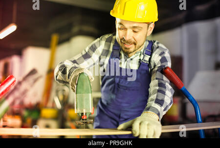 Sorridente uomo di lavoro mettere in pratica le sue abilità con potenza il puzzle in officina Foto Stock