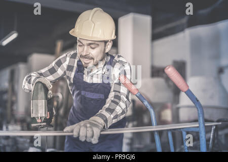 Sorridente uomo di lavoro mettere in pratica le sue abilità con il seghetto alternativo di potenza al workshop Foto Stock