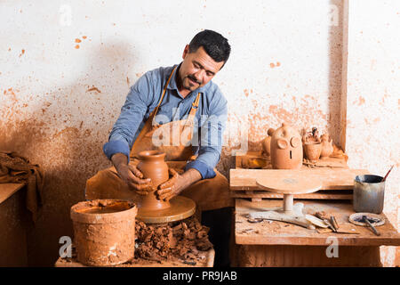 Felice uomo anziano rendendo pot con ruota di ceramiche in studio Foto Stock