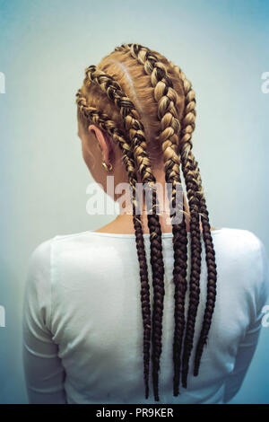 Ragazza con un creative acconciatura dalla stretta trecce di seduta sul davanzale Foto Stock