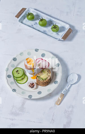 Uova sode sulla piastra di fresco con verdure tagliate a fette servita con pane integrale Foto Stock