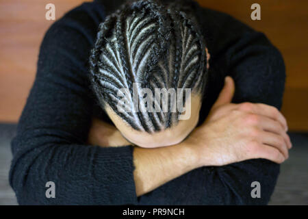 Trecce di piccole dimensioni sulla sua testa uomo con la faccia coperta, capelli scuri, Schot Foto Stock