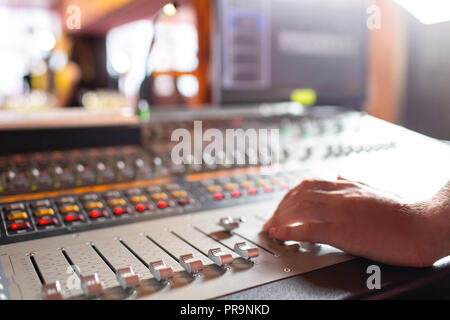 Maschio a mano il fader di comando sulla console. Per la registrazione del suono miscelazione in studio con scrivania da parte di un tecnico o di un produttore di musica Foto Stock