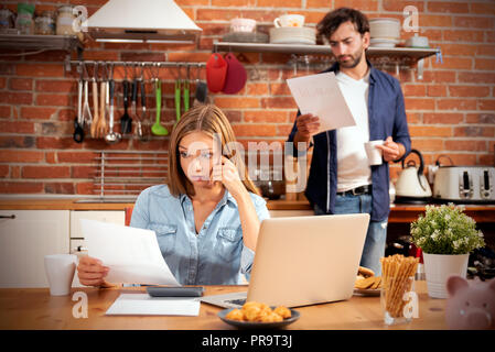 Coppia giovane in risparmi e home concetto di bilancio. Gestione delle finanze, tasse utilizzando una calcolatrice e laptop. Foto Stock