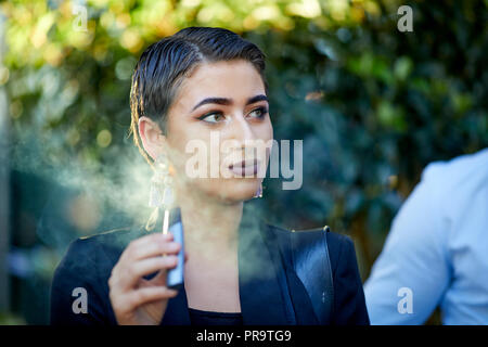 La gente di fumare utilizzando vape happing penne in Manchester Foto Stock