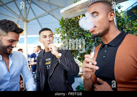 La gente di fumare utilizzando vape happing penne in Manchester Foto Stock