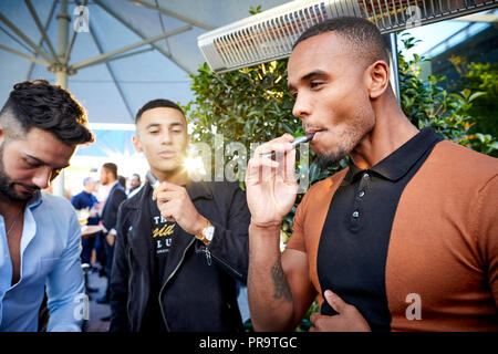 La gente di fumare utilizzando vape happing penne in Manchester Foto Stock