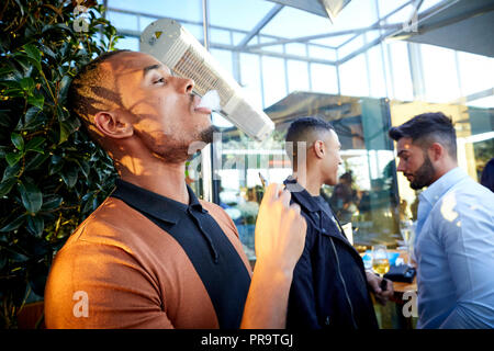 La gente di fumare utilizzando vape happing penne in Manchester Foto Stock