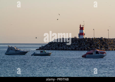 Barche in mare e faro rosso Foto Stock