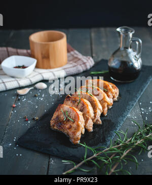 Arrosto di costolette di maiale con rosmarino fresco su sfondo scuro Foto Stock