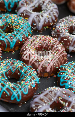 Ricoperta di cioccolato ciambelle con fori e spruzza in rosa e in blu Foto Stock