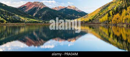 Nuvole riflettono in increspata lago di cristallo sotto le montagne rosse in autunno in Uncompahgre National Forest a sud di Ouray, Colorado. (Panorama) Foto Stock