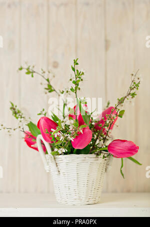 La molla bouquet di tulipani rosa con rami di un albero di fioritura di una luce sullo sfondo di legno. Messa a fuoco selettiva. Foto Stock