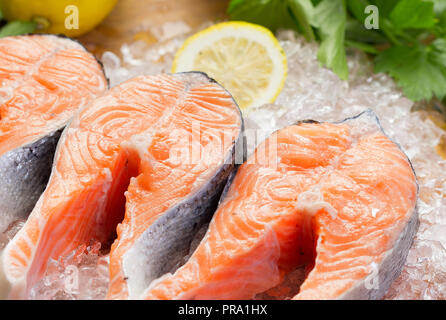 Vista ravvicinata di filetti di salmone su ghiaccio con verdi e limone Foto Stock